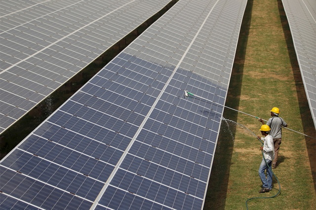 File photo of workers cleaning photovoltaic panels inside a solar power plant in Gujarat